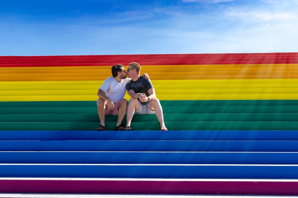 Two men kissing on rainbow flag steps