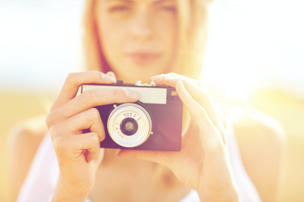 Close up of woman photographing with film camera by dolgachov