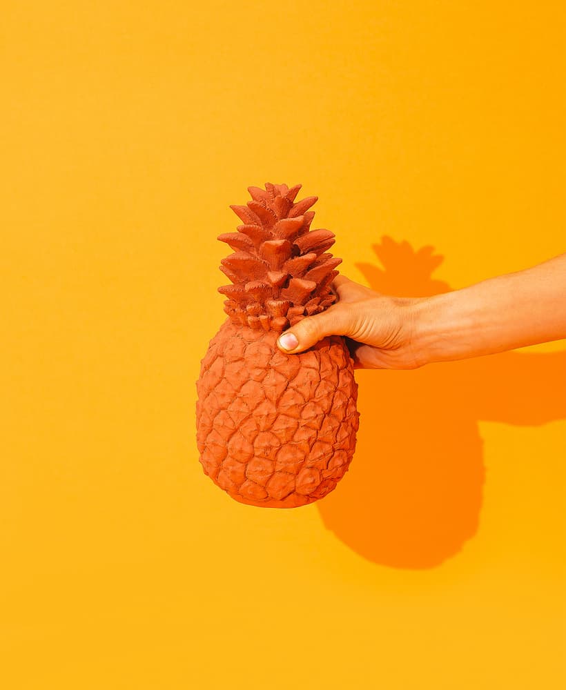 Monochromatic Product Photography - Yellow Color Palettes - Hand holding creative pineapple on yellow background