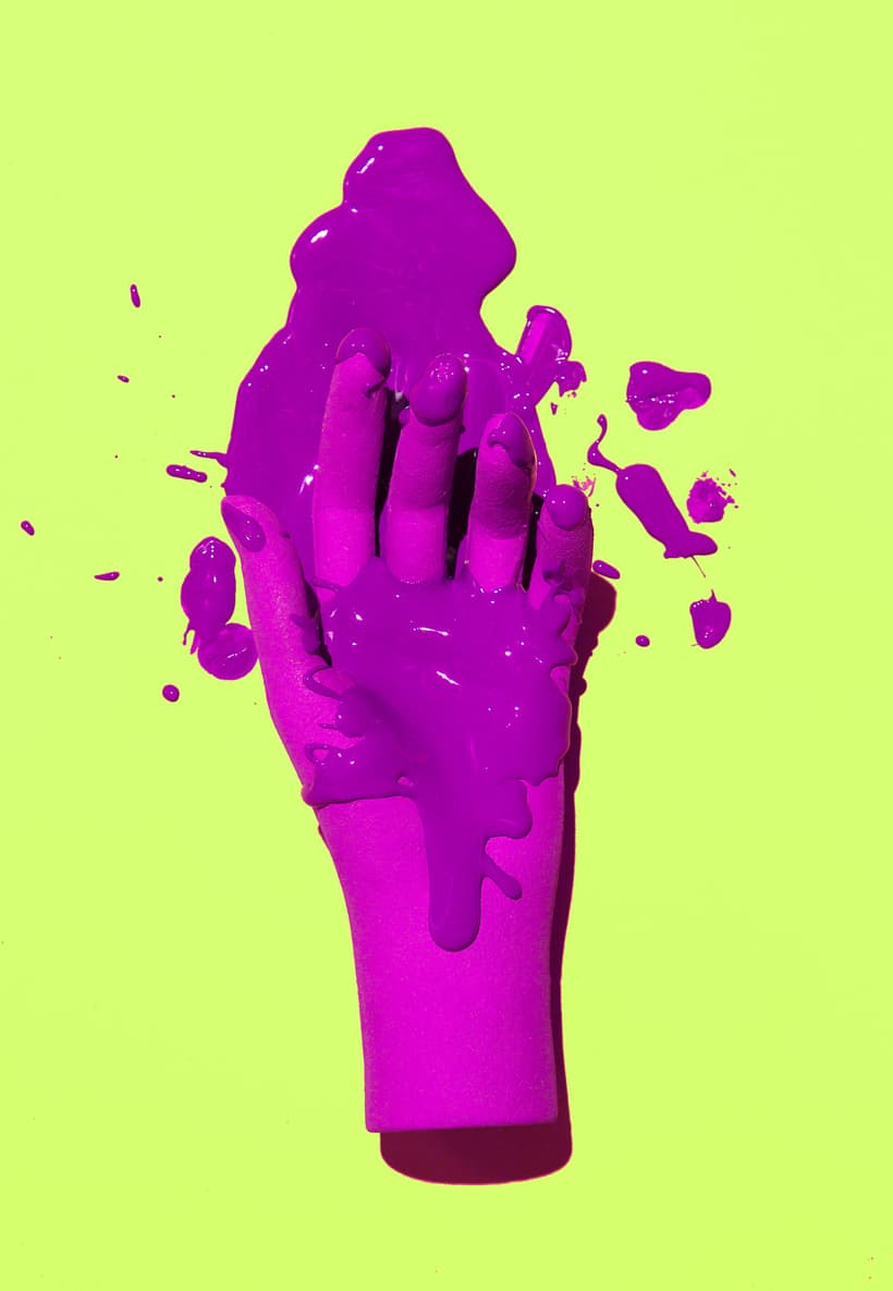 Fake hand and stain of purple paint on fresh green background. Minimalist creative wallpaper
